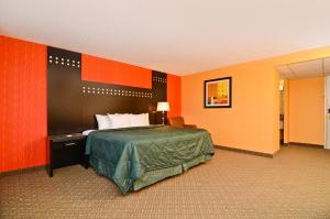 a hotel room with a bed and orange walls at Travelodge by Wyndham Absecon Atlantic City in Absecon