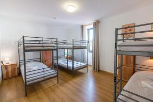 Change The World Hostels - Açores - Ponta Delgada في بونتا ديلغادا: ثلاثة أسرة بطابقين في غرفة مع أرضيات خشبية
