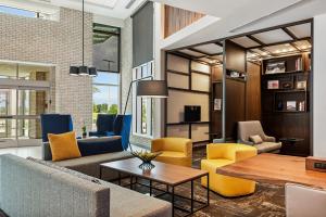 Hyatt Place Tampa/Wesley Chapel في لوتز: غرفة معيشة مع كراسي صفراء وزرقاء وطاولة