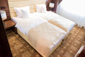 two beds in a hotel room with white sheets and pillows at Hotel Bucovina in Suceava