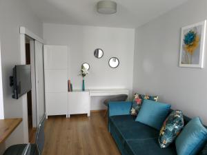 uma sala de estar com um sofá azul e uma televisão em Apartament 88 em Cracóvia
