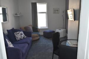 a living room with a blue couch and a window at Adelaide Apartments 2 in Blackpool