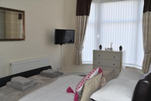 a bedroom with a bed and a tv on the wall at Adelaide Apartments in Blackpool
