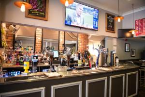 a bar in a restaurant with a tv above it at Thomas James Hotel in Leamington Spa