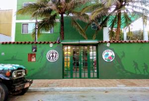 a green building with palm trees in front of it at Pousada Arraial Caribe in Arraial do Cabo