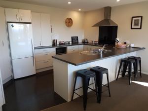 a kitchen with a sink and a counter with stools at Travels Rest in Franz Josef