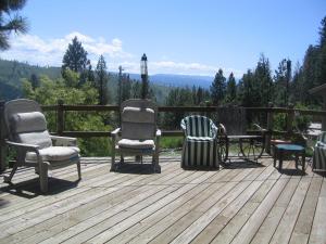 una terraza con 3 sillas y una mesa. en Whitebird Summit Lodge, en Grangeville