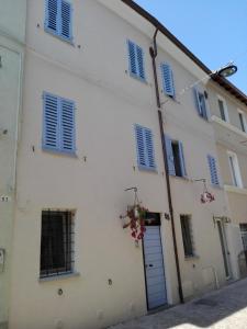 a white building with blue shuttered windows and a door at Tambien B&B in Pesaro