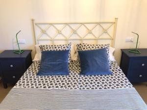 a bed with two blue pillows and two night stands at Apartment Jardines y Mar in Denia