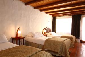 a hotel room with three beds and a window at Casa De Piedra in Purmamarca