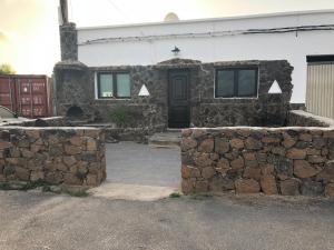 a stone house with a stone wall and a door at Yasmina in Lajares