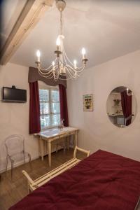 una camera con letto, tavolo e lampadario a braccio di Villa Goccia di Vino a La Morra
