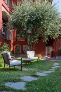 zwei Stühle und ein Tisch und ein Baum vor einem Gebäude in der Unterkunft Villa Goccia di Vino in La Morra