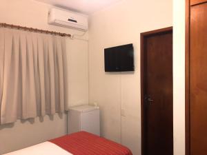 a small room with a bed and a television on the wall at Hotel Giordano Centro in São João da Boa Vista