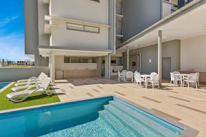 a patio area with chairs, a pool and a pool table at Aquarius Kawana in Kawana Waters