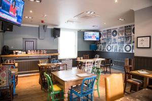 a dining room with tables and chairs and televisions at Thomas James Hotel in Leamington Spa