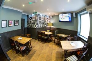 een restaurant met houten tafels en stoelen en een televisie bij Thomas James Hotel in Leamington Spa