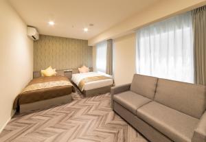 a hotel room with a couch and a bed at SARASA HOTEL Shin-Osaka in Osaka