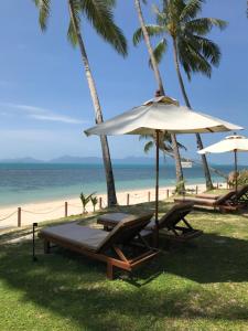 a beach with two chairs and an umbrella and the ocean at Lennon Maison in Mae Nam