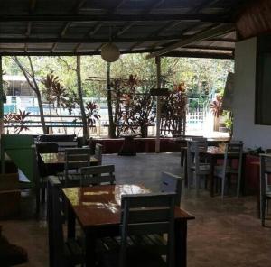 a restaurant with wooden tables and chairs and a large window at Villa Hermosa de Tambopata Casa Hospedaje & Hostel in Puerto Maldonado