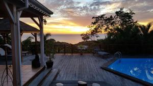 a sunset over a patio with a swimming pool at Les jardins de Cousinière in Vieux-Habitants