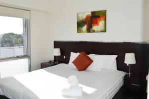 a bedroom with a bed with white sheets and a window at Adara St Kilda in Melbourne