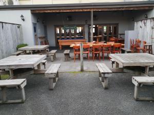 un grupo de mesas de picnic y sillas frente a un restaurante en Horse and Jockey Inn, en Matamata