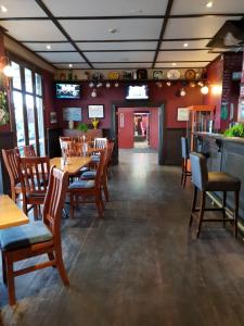 un restaurante con mesas y sillas de madera y un bar en Horse and Jockey Inn, en Matamata