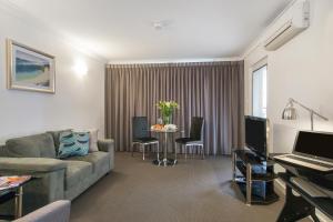 a living room filled with furniture and a tv at The Peninsula Riverside Serviced Apartments in Perth