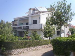 a large white building with trees and bushes at Apartments Lukacic in Krk