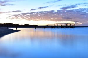 a sunset over the water with a pier at Kalbarri Sunset Villa in Kalbarri