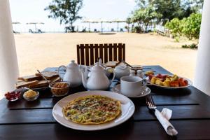 a table with a plate of food and tea on the beach at Ladja Beach Resort in Ambalantota