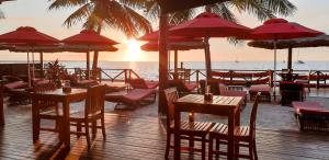 ein Restaurant am Strand mit Tischen und Sonnenschirmen in der Unterkunft Ramada Suites by Wyndham Wailoaloa Beach Fiji in Nadi