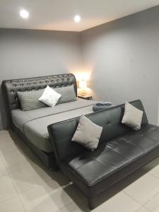 łóżko z czarną skórzaną kanapą w pokoju w obiekcie Asia's Beach Apartments w mieście Sattahip