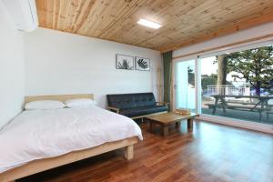 sypialnia z łóżkiem i kanapą oraz patio w obiekcie Seasidepine Pension w mieście Yeosu