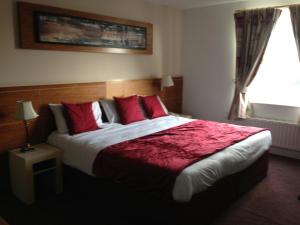 sypialnia z dużym łóżkiem z czerwonymi poduszkami i oknem w obiekcie Ashbourne House Hotel w mieście Ashbourne