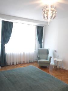 1 dormitorio con silla azul y lámpara de araña en Apartment Bianco Central, en Sibiu