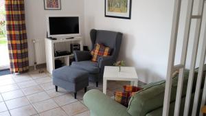 a living room with two chairs and a tv at Gästehaus Luck in Ditzum