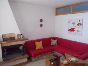 czerwona kanapa w salonie z kominkiem w obiekcie Cottage in montagna Montemonaco w mieście Montemonaco