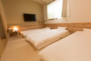 2 łóżka w pokoju z telewizorem z płaskim ekranem w obiekcie Onya Tachibana w mieście Kioto