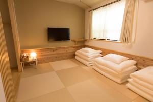 Pokój z białymi poduszkami i telewizorem z płaskim ekranem w obiekcie Onya Tachibana w mieście Kioto