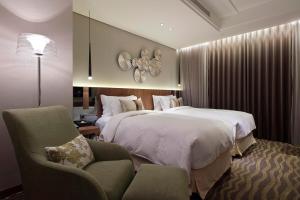 una camera d'albergo con due letti e una sedia di Green World JianPei a Taipei Altre 37 foto