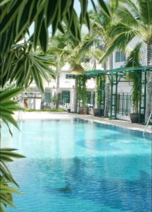 a large swimming pool with palm trees around it at Baan Klang Condo Hotel Hua Hin in Hua Hin