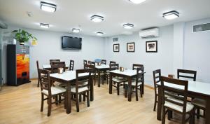 comedor con mesas y sillas y TV de pantalla plana en Hostal T4 en Paracuellos de Jarama