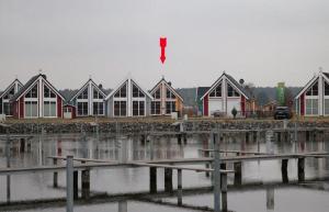 a row of houses on a dock next to a body of water at Skandinavisches-Ferienhaus-2-Reihe-zum-Wasser-fuer-6-Personen in Zerpenschleuse