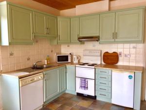a green kitchen with white appliances and green cabinets at Birch Tree Cottage in Westport
