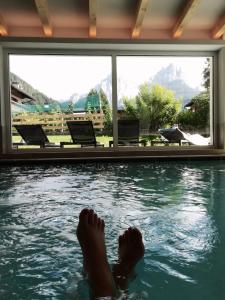 a person with their feet in a swimming pool at Hotel El Paster in Pozza di Fassa