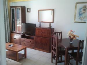 a living room with a dining room table and a television at Apartamentos Ocaña in Cala de Finestrat