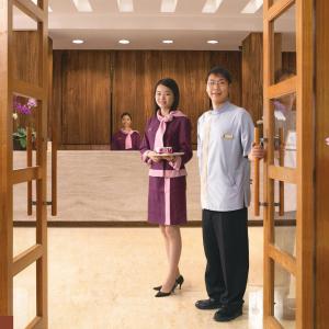 Un uomo e una donna in piedi in un corridoio di Hua Ge Hot Spring Hotel a Jiaoxi