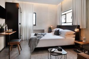 a bedroom with a large white bed and a table at The Vera in Tel Aviv